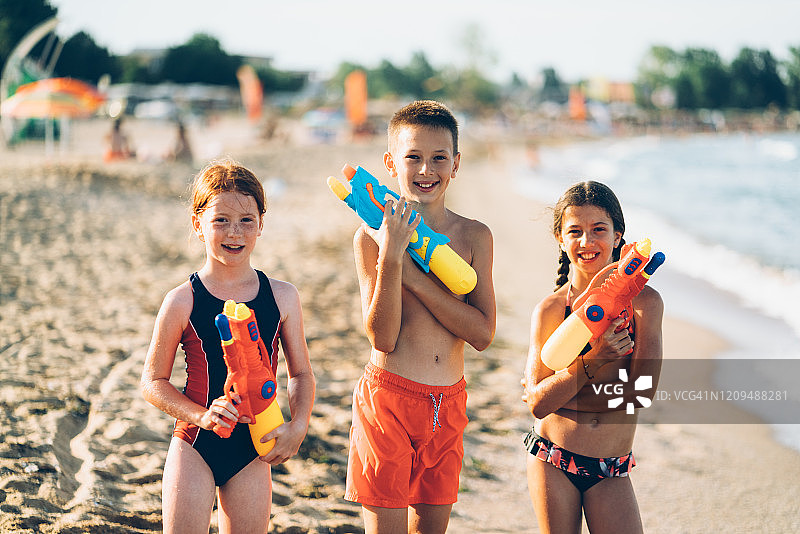 孩子们拿着水枪在海滩度假的肖像图片素材