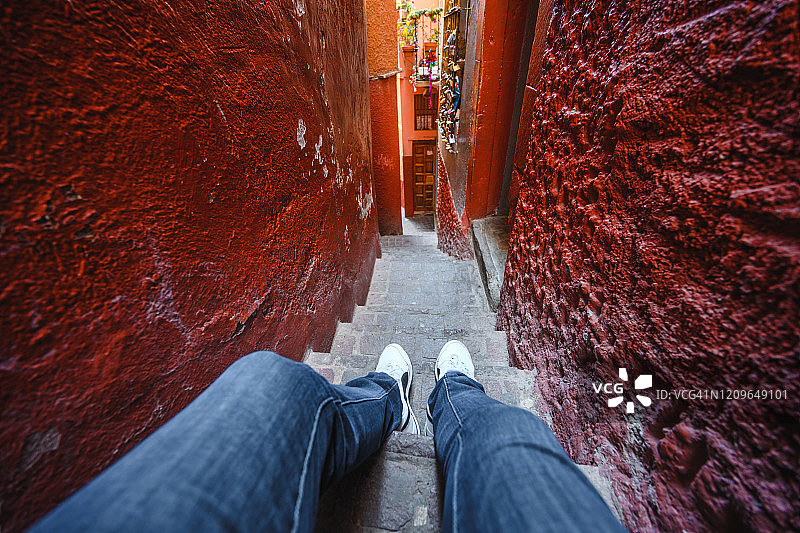 坐在墨西哥瓜纳华托狭窄小巷楼梯上的人的个人视角图片素材