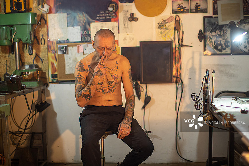 纹身男子在他的工作室吸烟图片素材
