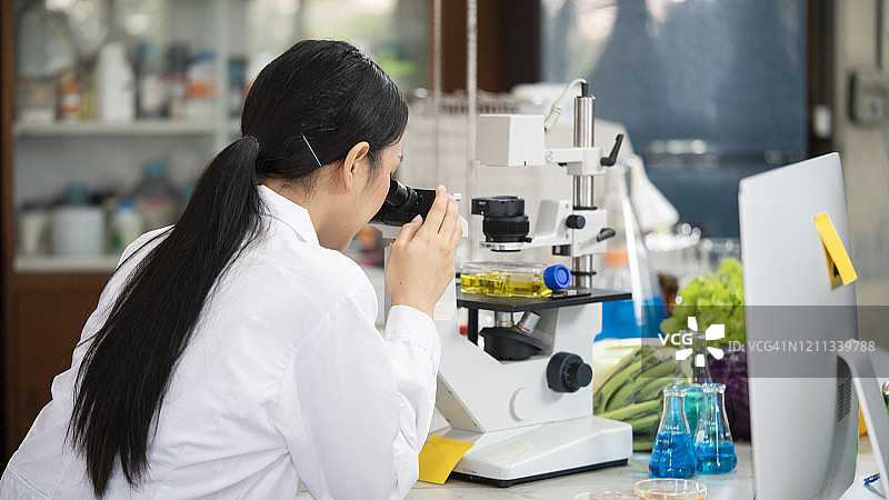 一位年轻科学家在实验室里使用显微镜的肖像图片素材