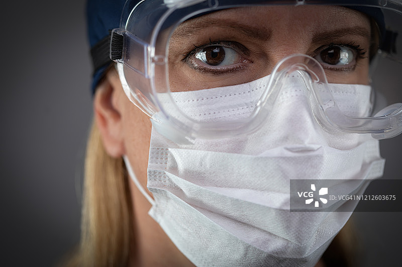 女医务工作者佩戴防护面罩和防护装备，以对抗黑暗背景图片素材