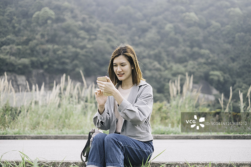 一位亚洲女性在徒步旅行时用手机给她的朋友发短信图片素材