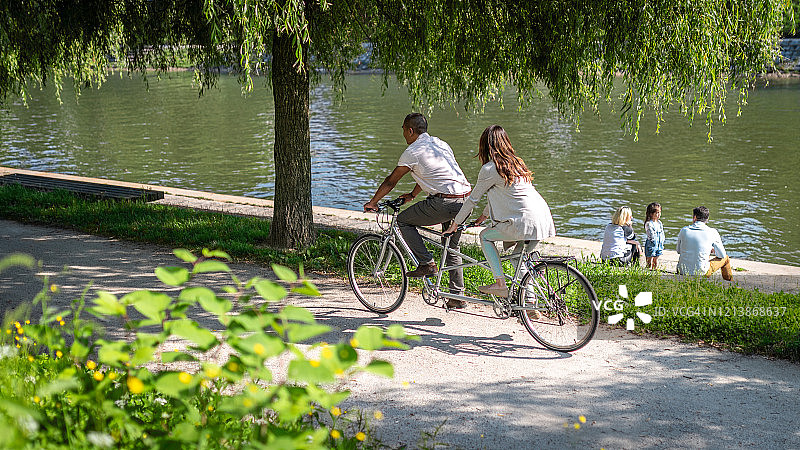 一对夫妇在河岸上骑双人自行车图片素材