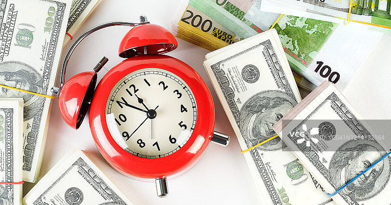 一堆纸币和欧元上的复古红色闹钟。时间就是金钱。经营理念。图片素材