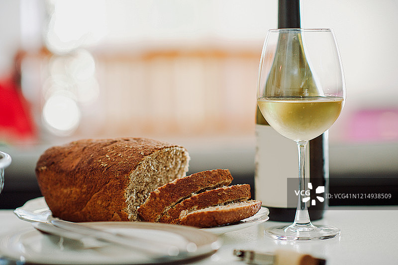 新鲜切好的面包配白酒瓶和玻璃杯图片素材