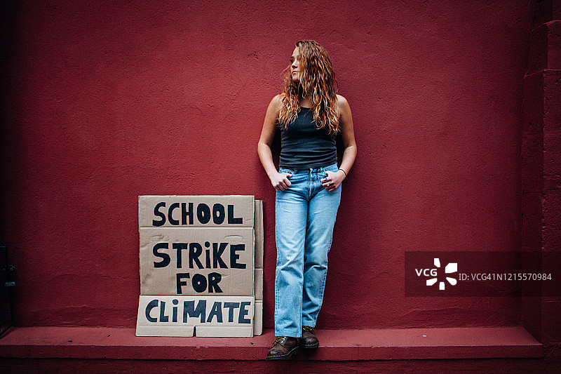 一名少女举着气候学校罢工抗议的牌子图片素材