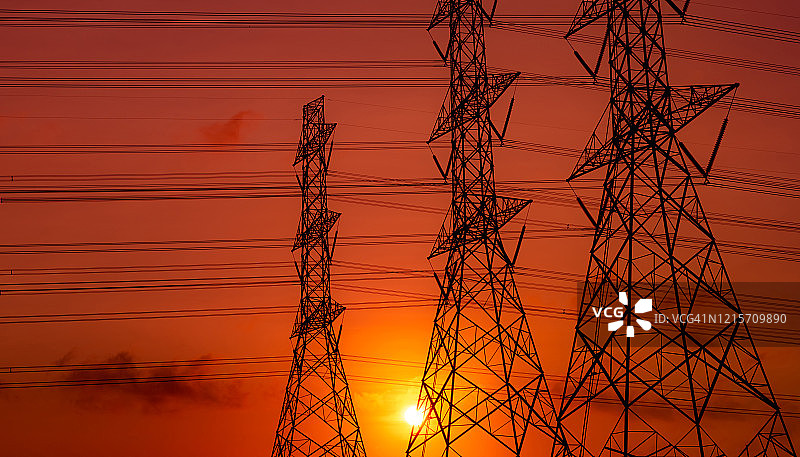 高压塔和电线与日落的天空。电力波兰人。动力和能源概念。高压电网塔架带电线电缆。美丽的橙红色日落天空。基础设施。图片素材
