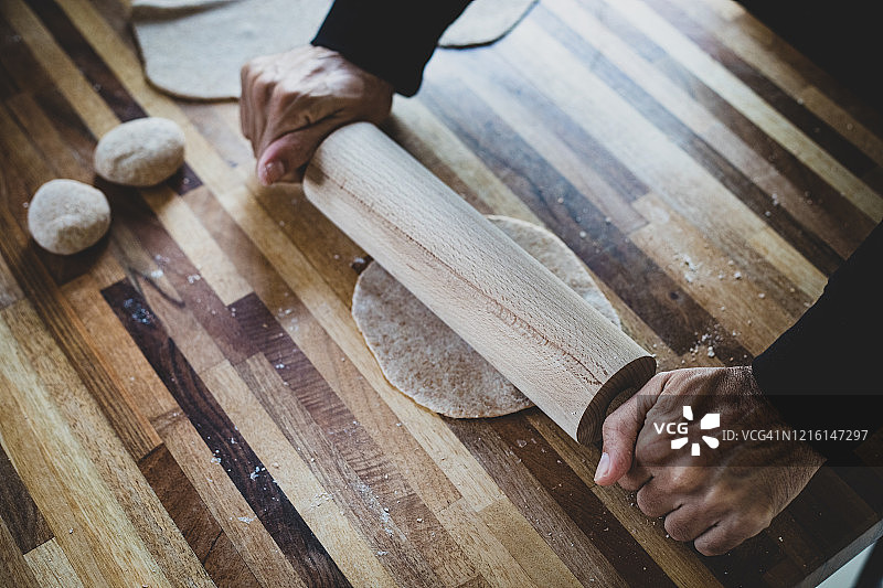 一个男人正在用橡胶、木头、木头滚筒做薄饼图片素材
