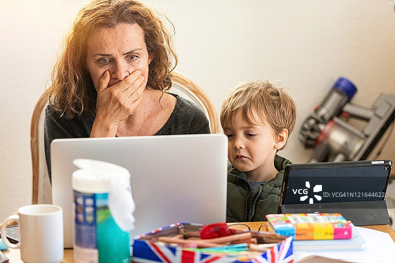 非常悲伤的成熟女性和她的儿子一起在电脑上看新冠肺炎新闻图片素材