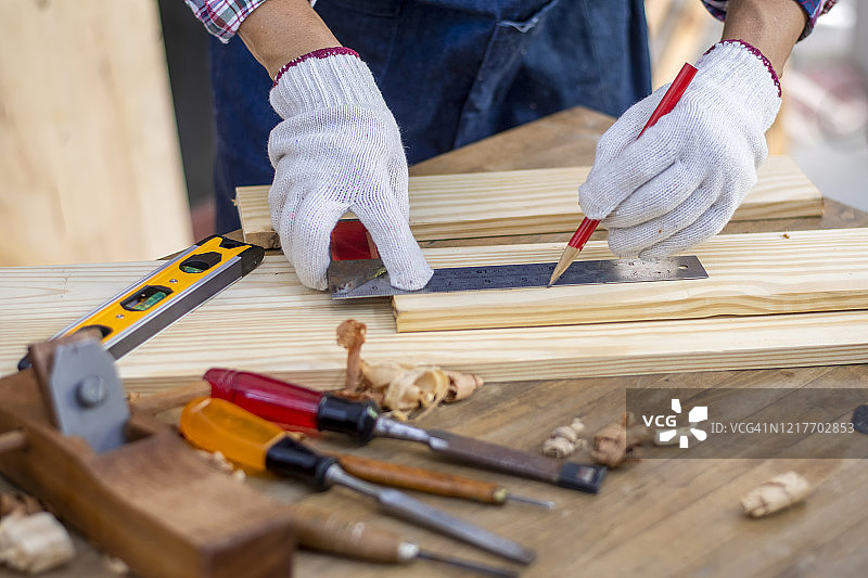特写:强壮的男性的手在木工作坊制作家具时用刨刀削一块木头图片素材