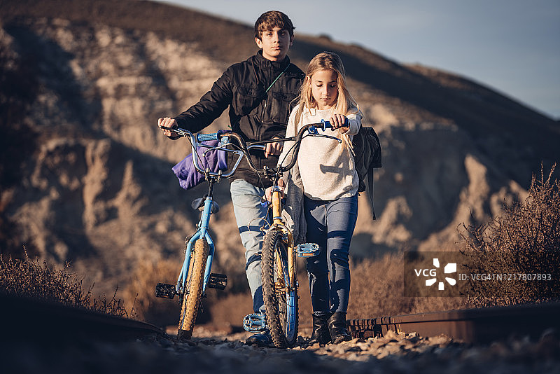 男孩和女孩骑着自行车在乡村风景中散步图片素材
