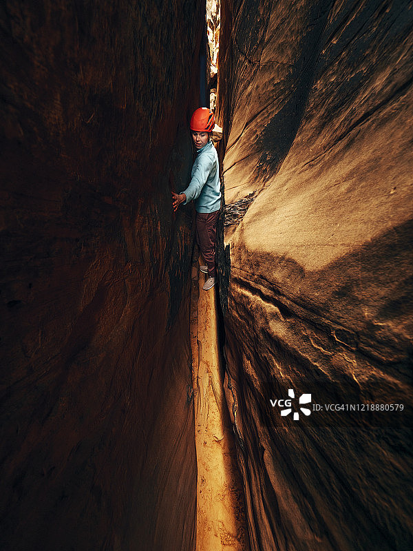 一名年轻女子奋力向上，穿过一条狭窄的峡谷图片素材