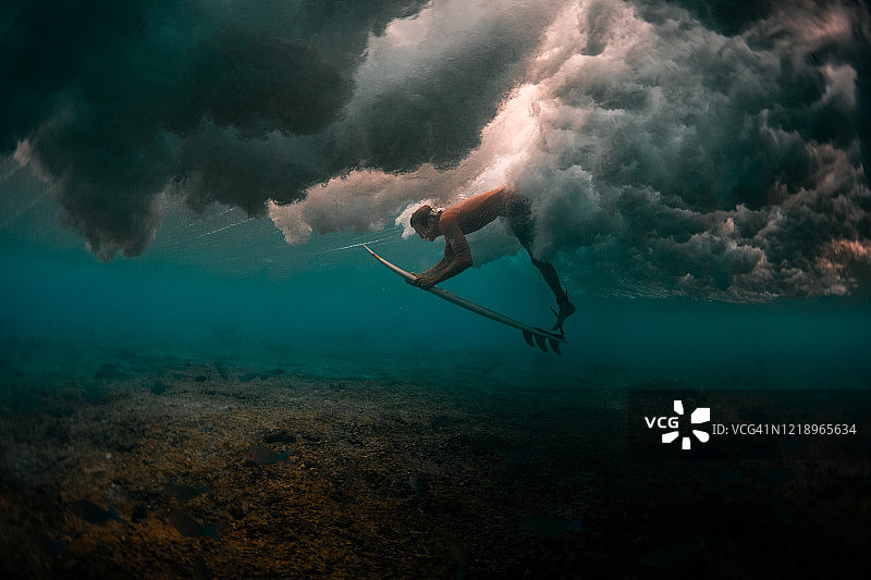冲浪者潜入强大的波浪下安全地通过它图片素材