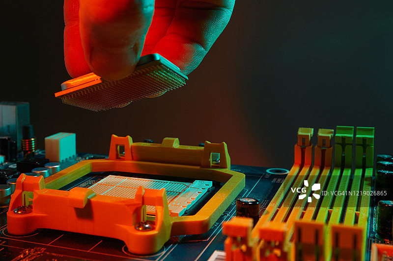 工程师修理工拿着芯片CPU插入电脑主板的插座。技术硬件的概念。图片素材