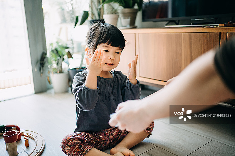 可爱的亚洲小女孩从她的手在眼睛，从她的父母的礼物和愉快的微笑在客厅在家里图片素材