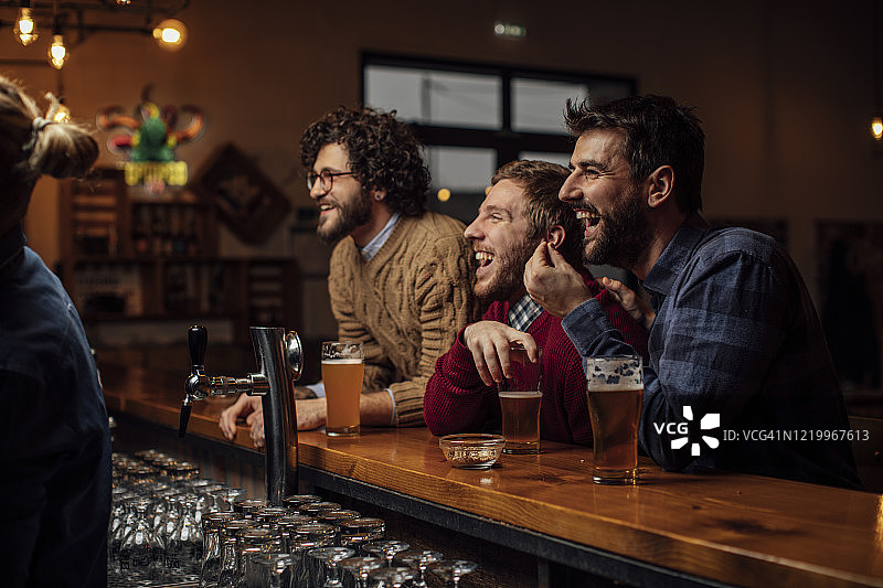 一群快乐的年轻人在酒吧喝啤酒看足球比赛图片素材