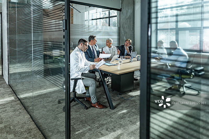 男性企业家在办公室开会时与医学专家交谈。图片素材