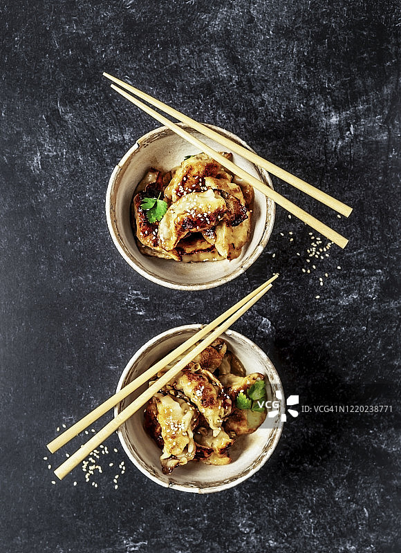 两碗饺子，用筷子夹在黑色的背景上图片素材
