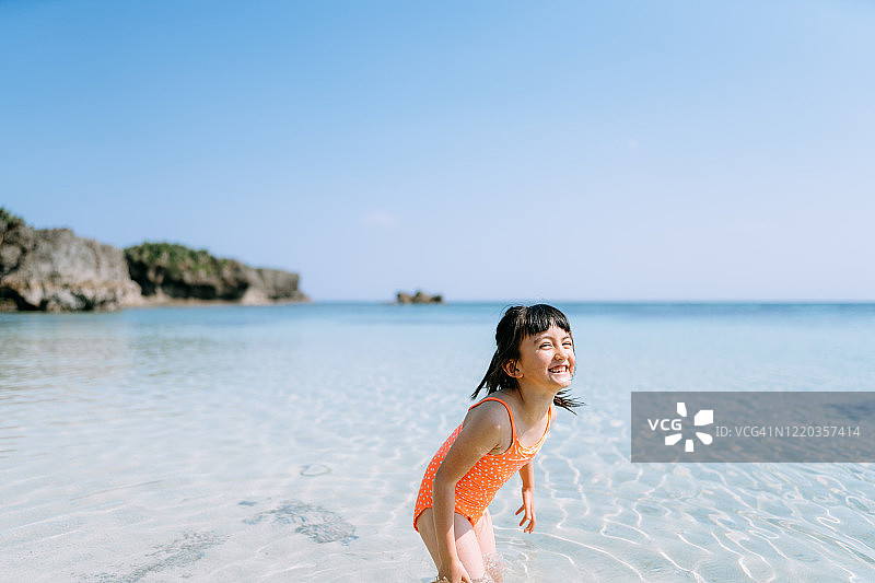 可爱的欧亚女孩玩在热带海滩水，冲绳，日本图片素材