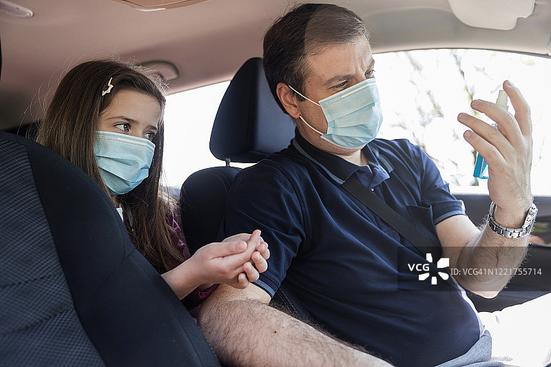 父亲和女儿在车里使用手消毒剂图片素材