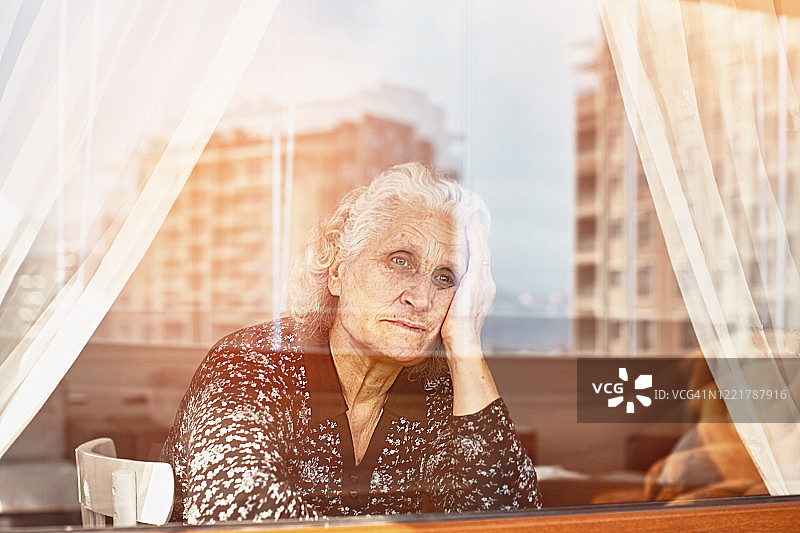 老妇人独自坐着，忧伤地望着窗外图片素材