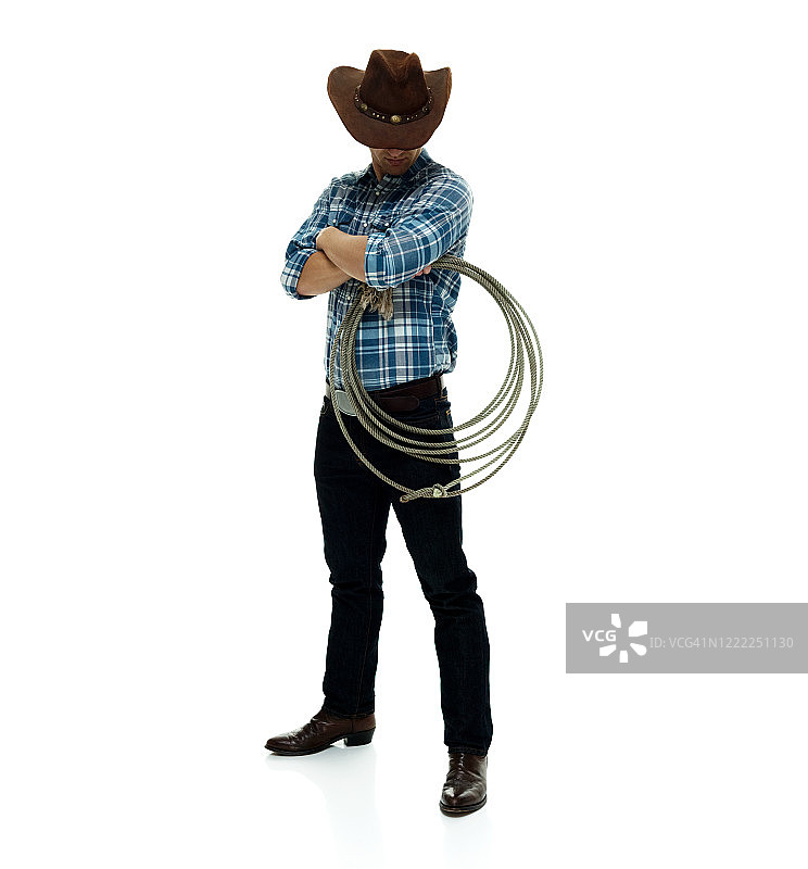 白人男性牛仔戴着牛仔帽，手持套索，用绳子站在白色背景前图片素材