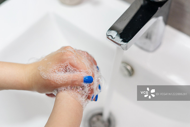 近距离观察不明白种人女性用肥皂泡沫在浴室水槽、水龙头、水龙头洗手，以清洁和消毒预防疾病，在家里的天俯视图图片素材