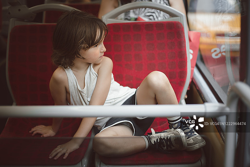 男孩坐在公共汽车上的两个座位上图片素材