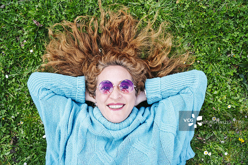 幸福的红发成熟女人的肖像躺在草地上图片素材