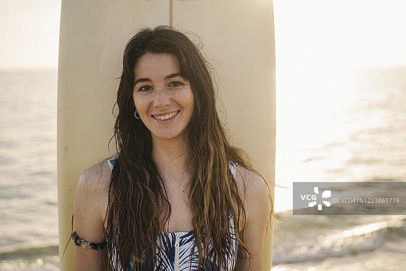西班牙阿尔梅里亚海滩上微笑的年轻女子与冲浪板的肖像图片素材