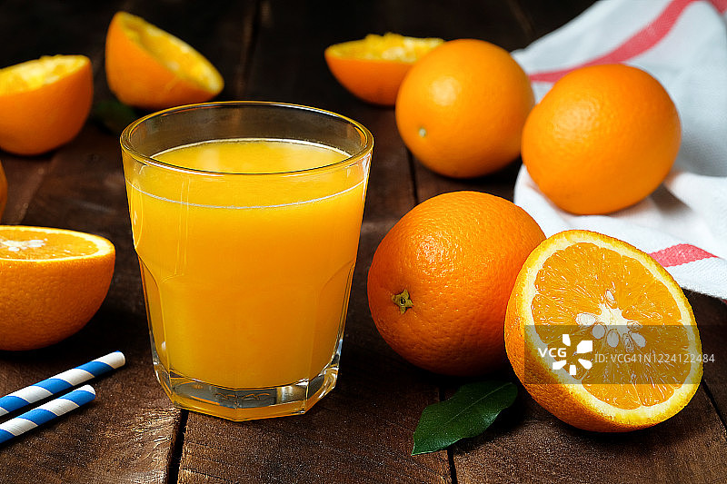木桌上放着一杯橙汁。图片素材