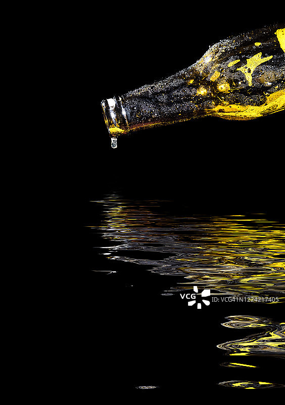 啤酒瓶在黑色背景上倒映在水面上。图片素材