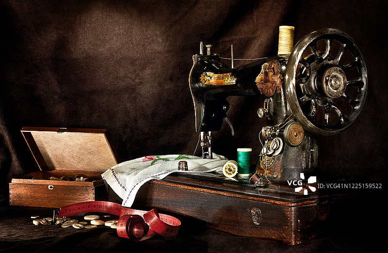 怀旧缝纫机与织物和设计设备在黑暗的场景图片素材