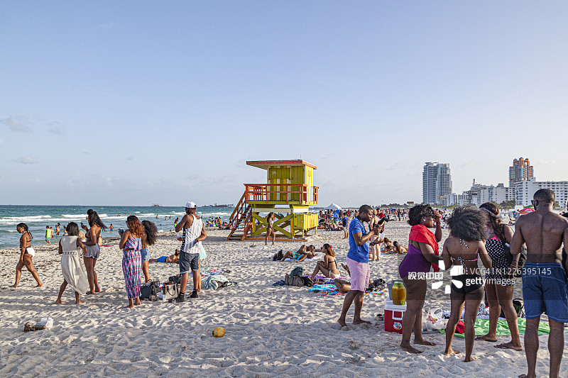 人们喜欢迈阿密海滩的南海滩，坐在五颜六色的救生员塔前图片素材