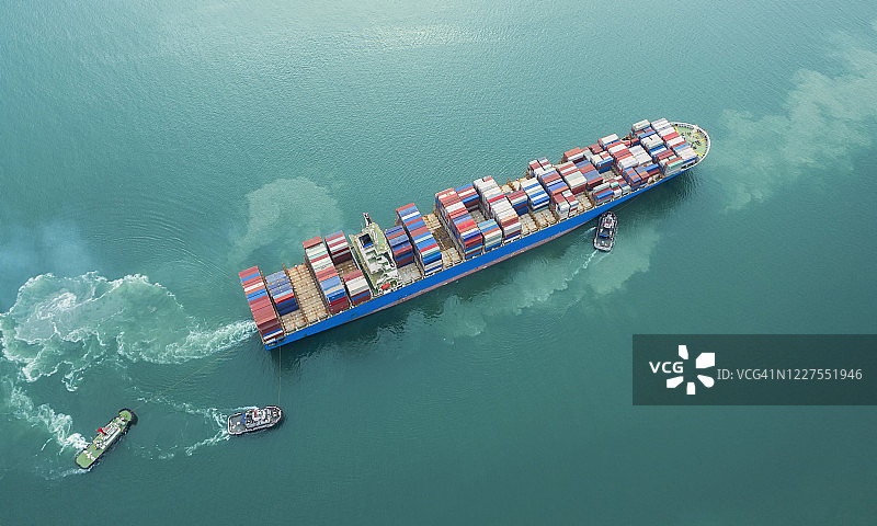 高空鸟瞰图拖船拖着集装箱货船前往码头码头或码头码头，进行商业物流、进出口、运输或运输。图片素材