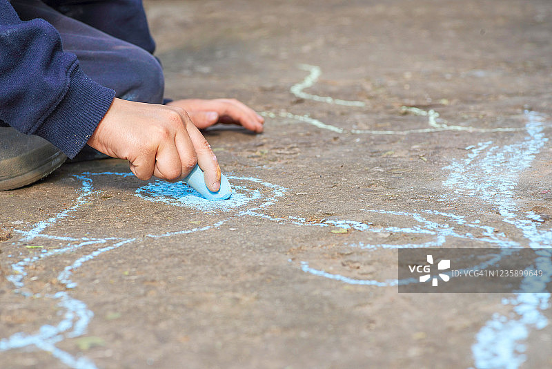 孩子在沥青上用粉笔画画。孩子画油画沥青概念。孩子在玩彩色粉笔。图片素材