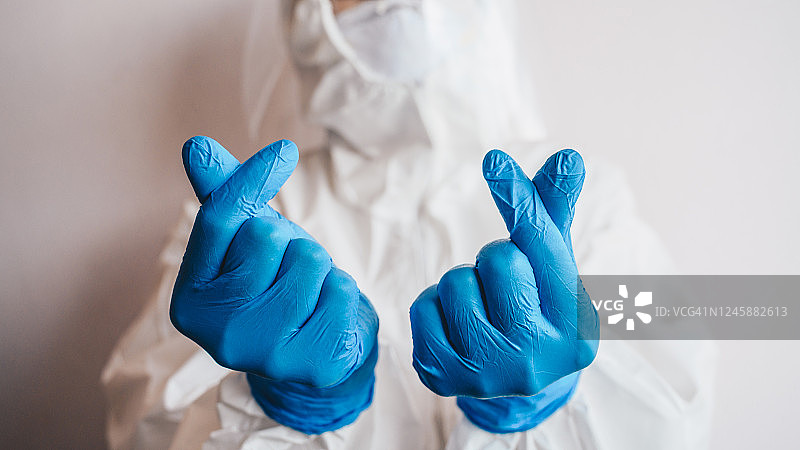 医护人员在医院工作时穿着防护服做迷你心脏手势的剪影。图片素材