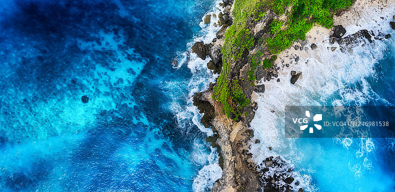 波浪和岩石作为背景从俯视图。蓝色的水背景从俯视图。从空中俯瞰夏日海景。巴厘岛,印度尼西亚。旅行——形象图片素材