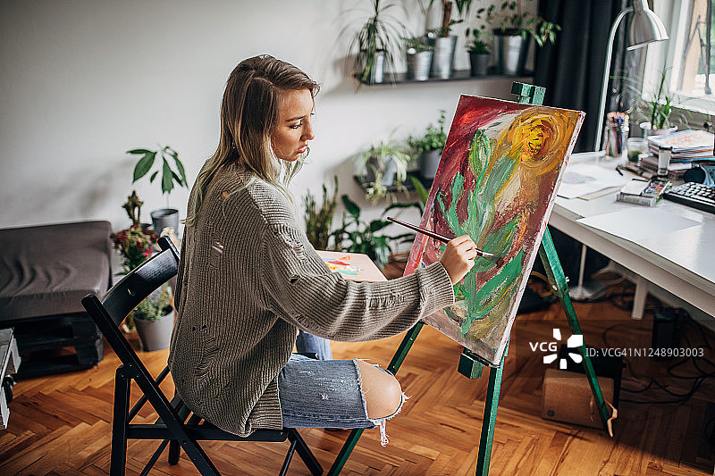 一位年轻的女艺术家在她的家庭画室里作画图片素材