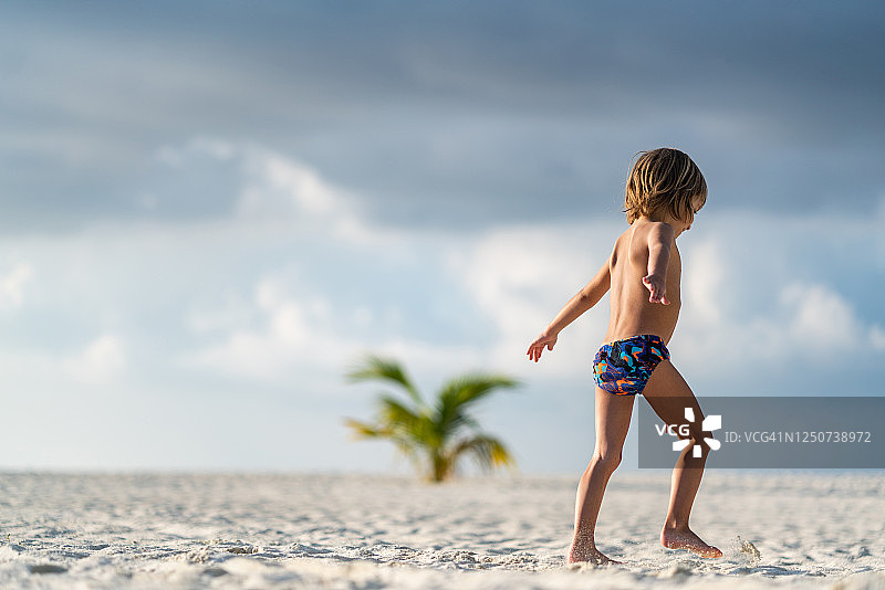 孩子举起手臂在海滩上奔跑图片素材