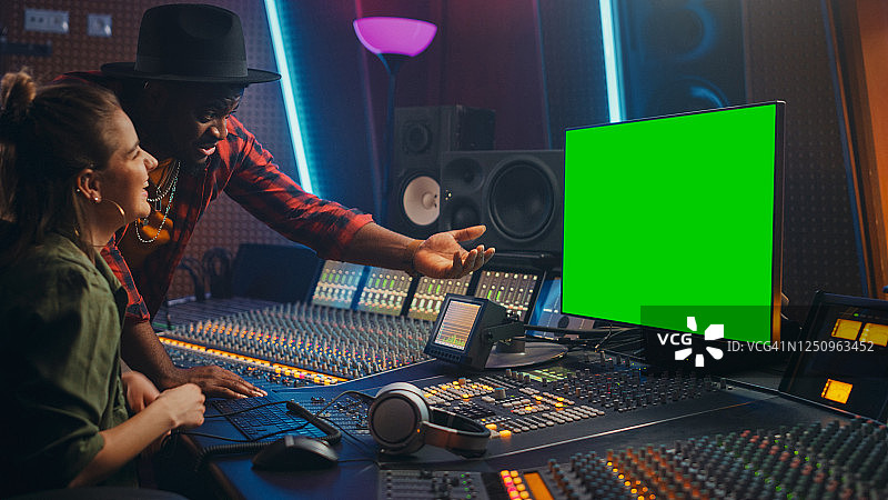 制作人和音频工程师一起工作在音乐录音室的新专辑，使用绿色屏幕电脑，控制台混合和创造热门歌曲。艺术家与音乐家合作图片素材