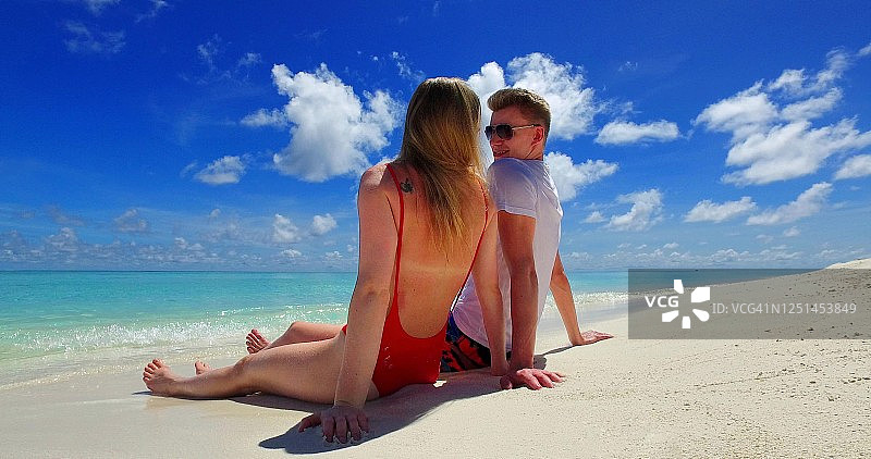 在夏天的蜜月假期里，一对浪漫的夫妇坐在海滩上愉快地聊天图片素材