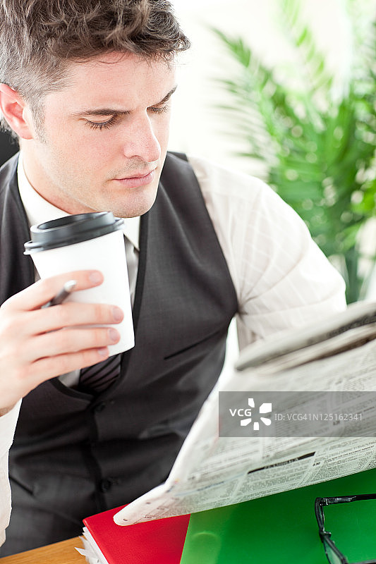 有魅力的商人一边喝咖啡一边看报纸图片素材