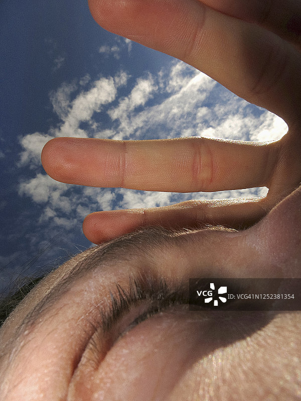 在晴朗的天空下，用手遮住女人的眼睛图片素材