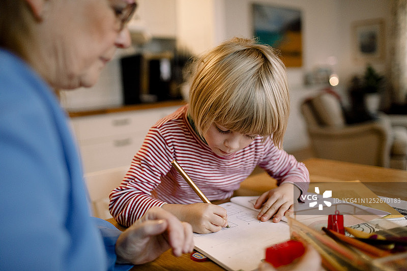 男孩在做作业，奶奶在餐桌上图片素材
