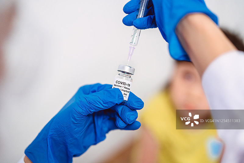 医生戴着防护手套，注射COVID-19疫苗，准备给女童接种COVID-19疫苗图片素材