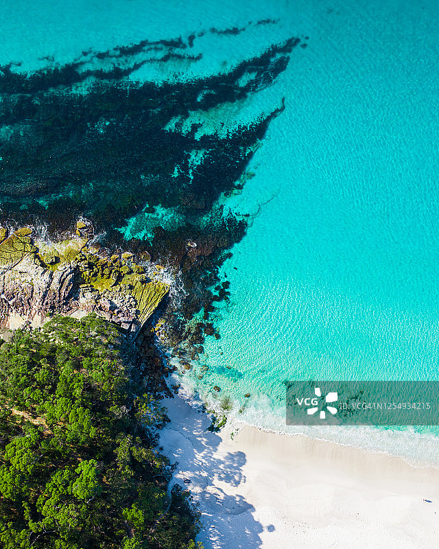 无人机拍摄的白色沙滩周围是树木和绿松石色的海水图片素材