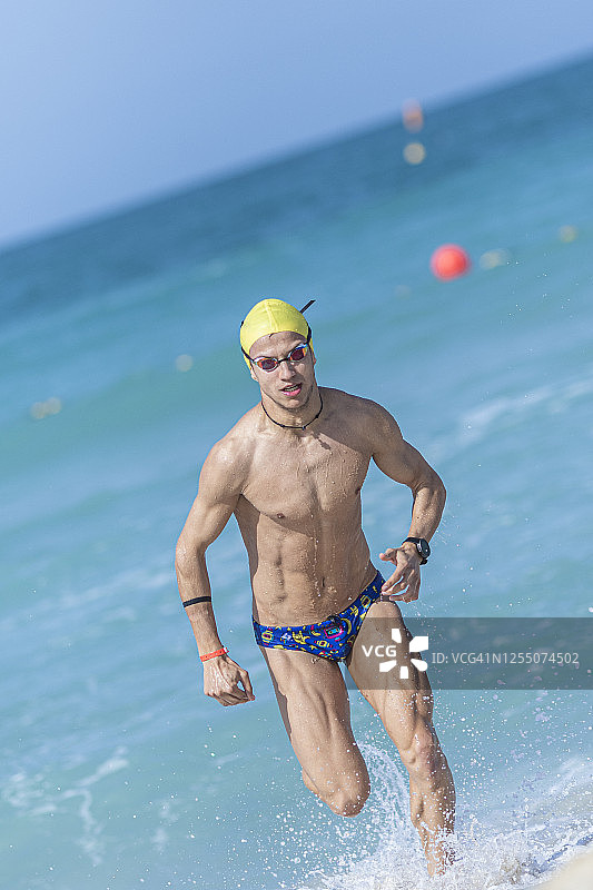 在阿拉伯联合酋长国迪拜海滩上跑步的男性游泳运动员图片素材
