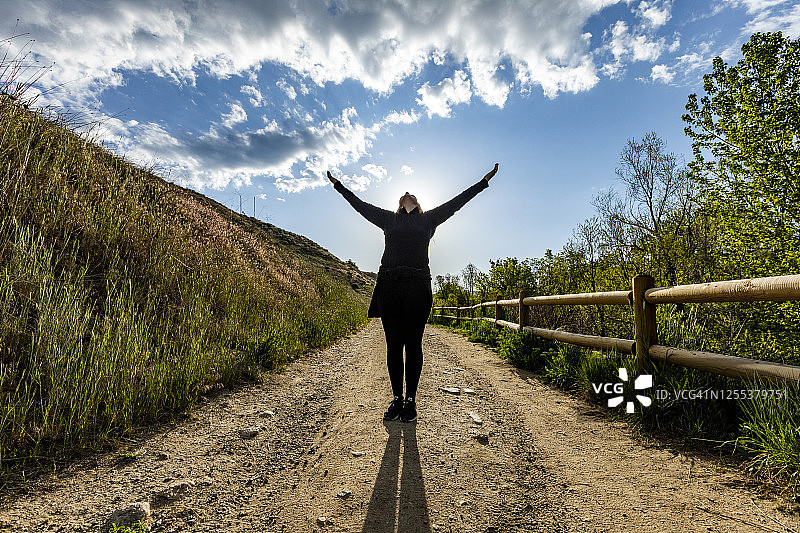 美国，爱达荷州，博伊西，一名女子高举双臂站在人行道上图片素材