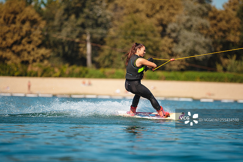 年轻女子用尾流板在水面上滑行图片素材